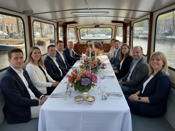 Group of people seated at a dinner table on a boat with floral centerpiece.