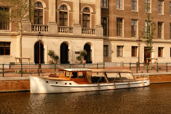 Vintage boat on canal, brick building in background.