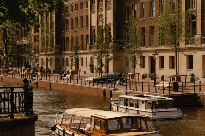 Canal with boats and historic building, cloudy sky.