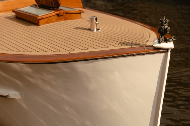 A wooden boat with a polished deck docked on calm water.