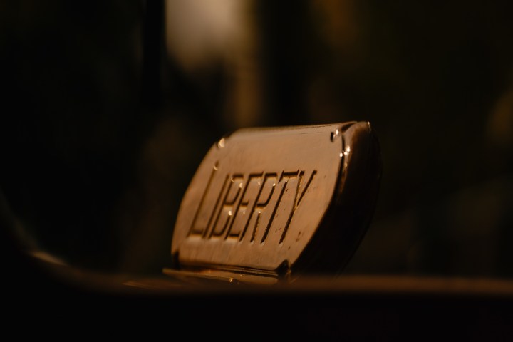 Close-up of a rusty metal sign with 'LIBERTY' in dim lighting.
