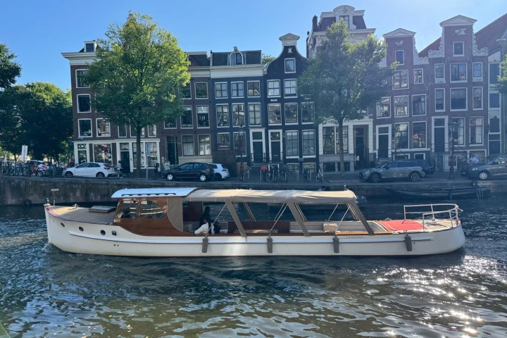 Classic wooden boat on a canal with historic buildings in the background.