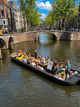 Canal with boat of people passing under bridges in a city with historic buildings.