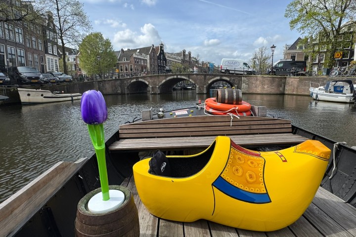 Yellow clog on boat with purple tulip in Amsterdam canal.