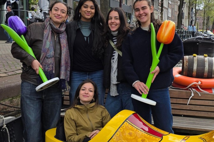Five people posing with large wooden shoes and tulip props outdoors.