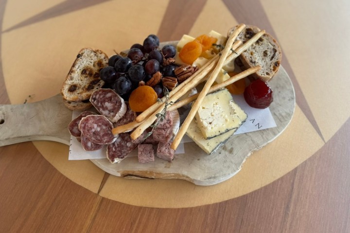 Charcuterie board with salami, grapes, cheese, bread, and dried fruit.
