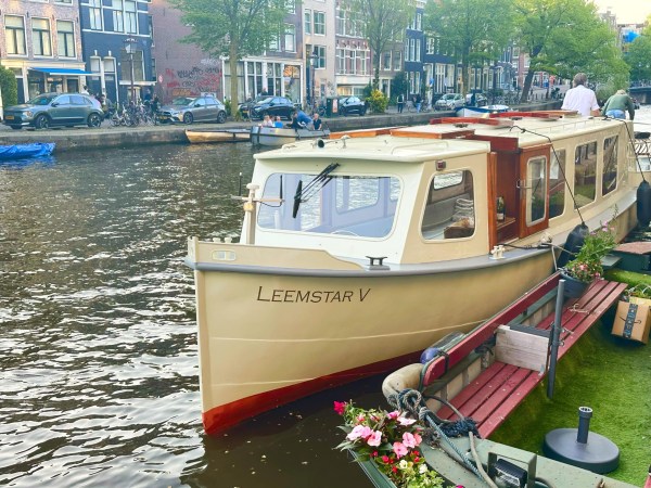 Boat named Leemstar V docked on a canal with trees and buildings in the background.