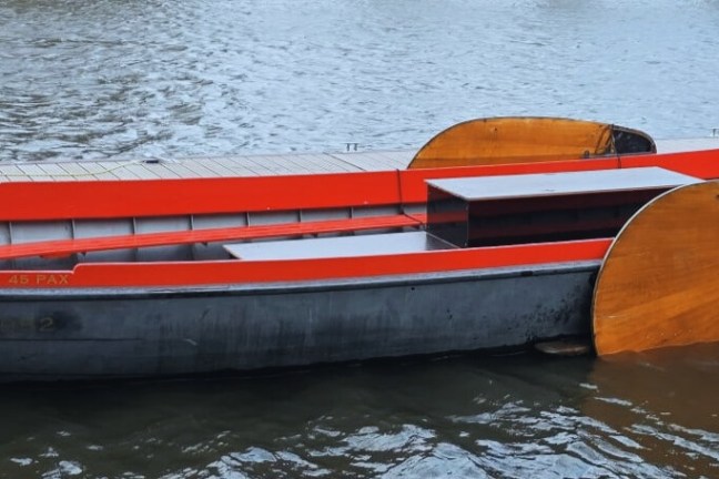 A black boat with orange seats and wooden panels floating on the water.