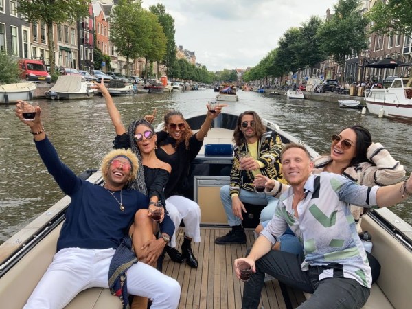Group of people enjoying drinks on a boat in a canal.