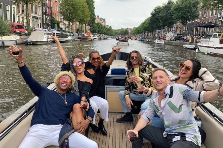 Group of people enjoying drinks on a boat in a canal.