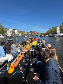 Group of people sitting on a boat in a canal on a sunny day.