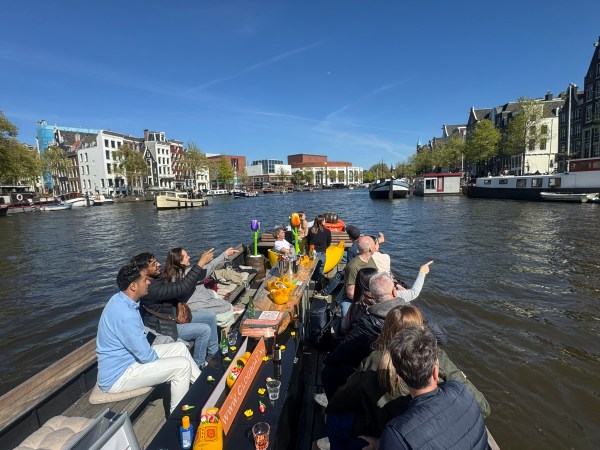 People on a boat enjoying a canal cruise with city buildings in the background.