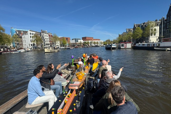 People on a boat enjoying a canal cruise with city buildings in the background.