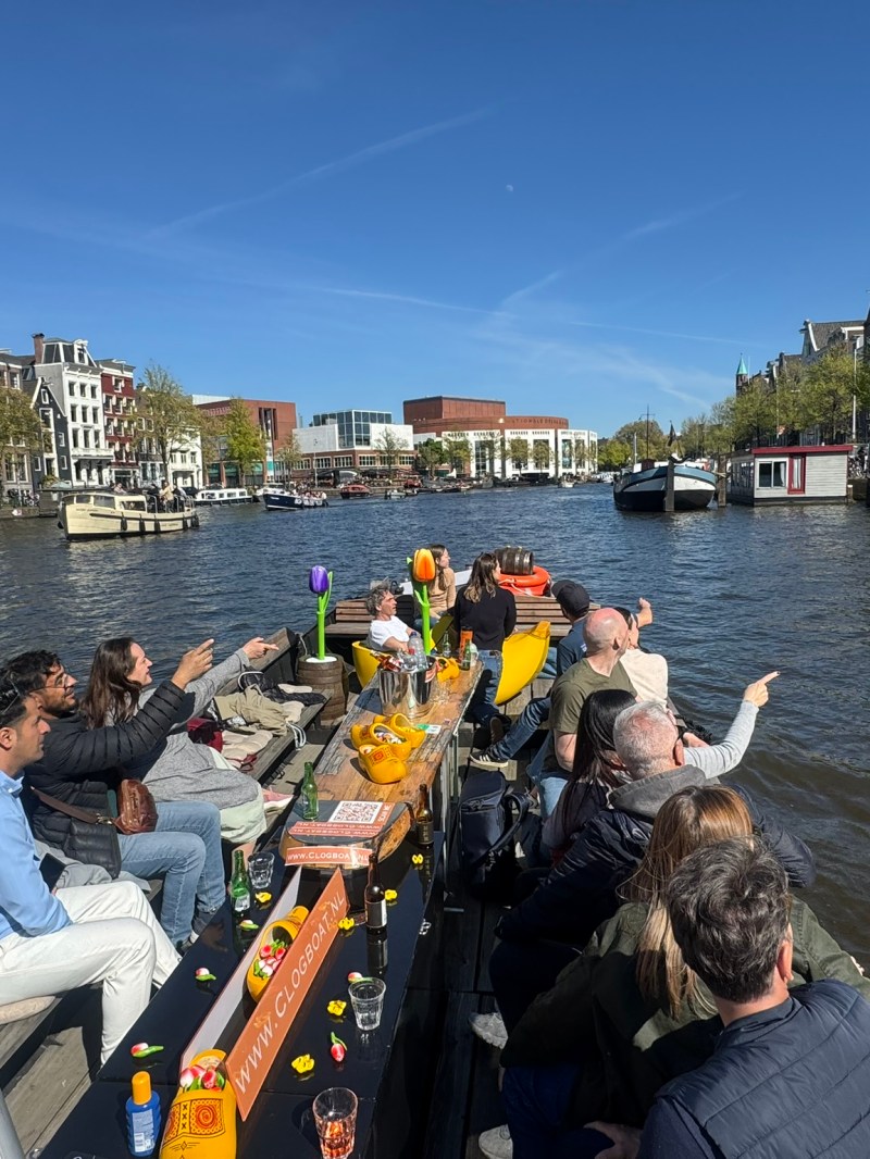 People on a boat enjoying a canal cruise with city buildings in the background.